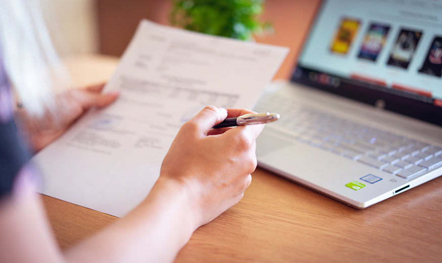 Femme lisant un document avec un stylo dans la main.