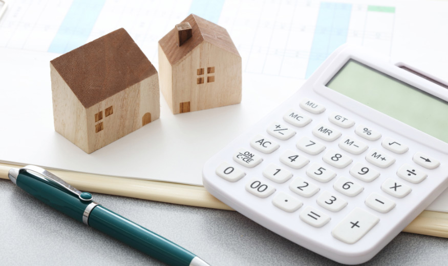 Maison miniature et calculatrice sur des plans de maison