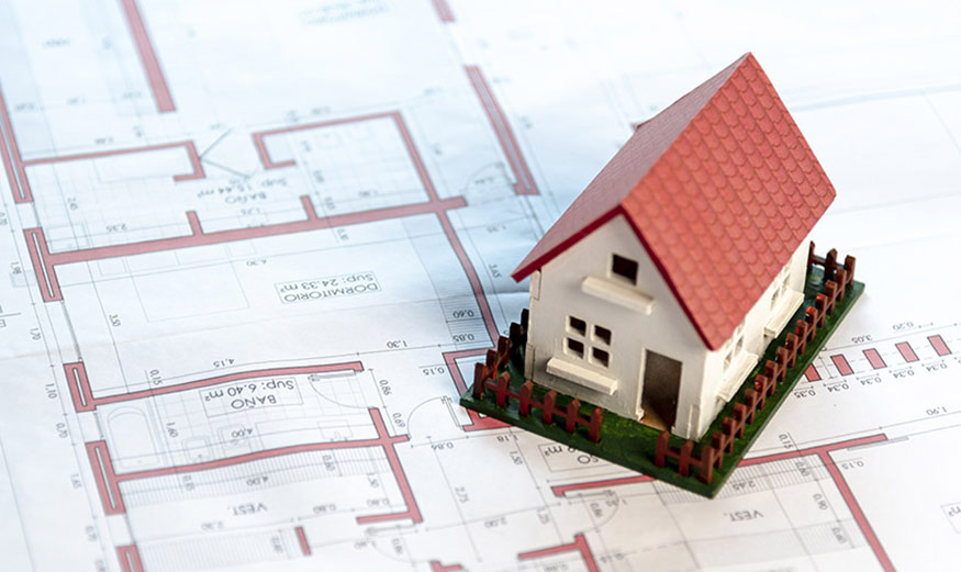 Maquette d’une maison posée sur des plans en papier.