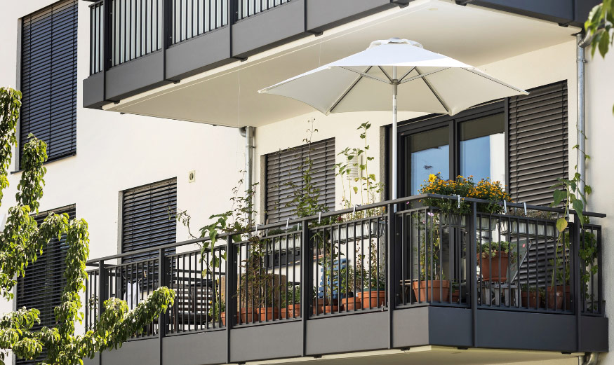 Balcon en copropriété aménagé, avec plantes en pot et parasol.
