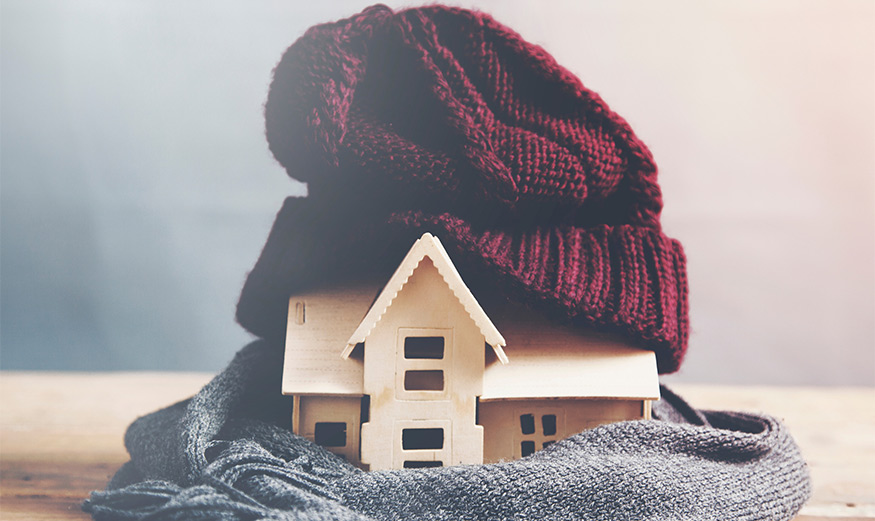 Petite maison protégée par le froid grâce à un bonnet et une écharpe.