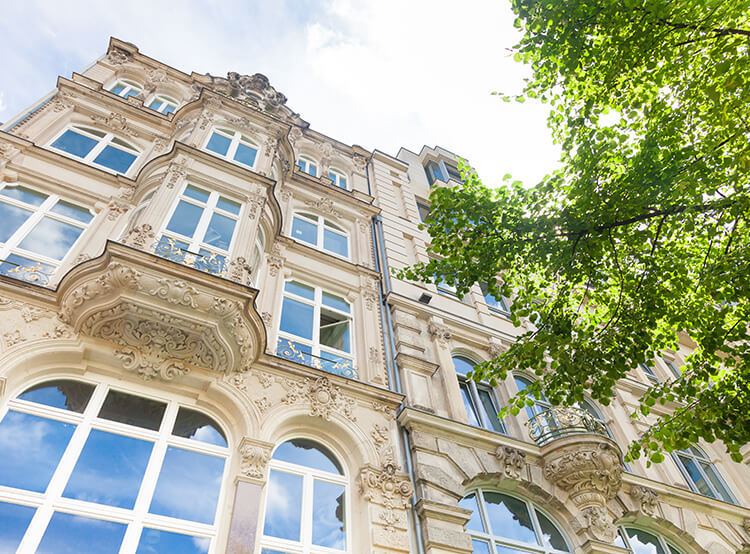 Vue du bas sur la façade d’un immeuble ancien prestigieux aux grandes fenêtres et moulures