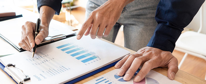 Deux hommes regardent des fiches de rapport et l’un d’eux écrit