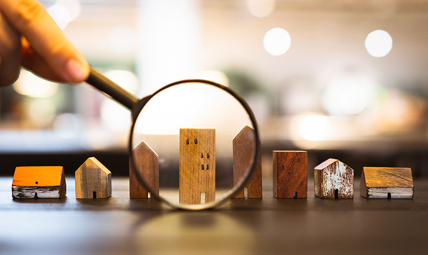 Une loupe montrant differentes petites maisons en bois.