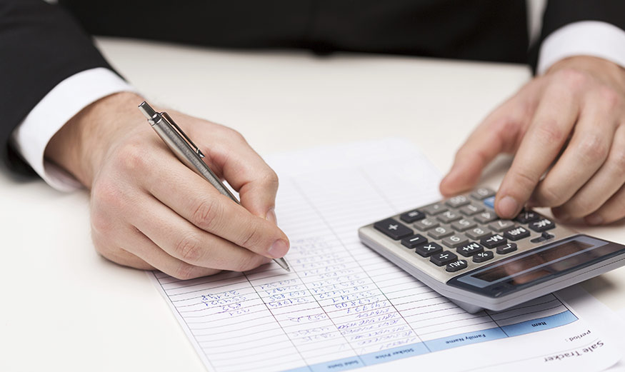 Personne tenant un crayon et calculant sur une calculatrice 