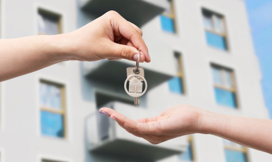 Une personne devant un immeuble remettant des clés d’appartement.