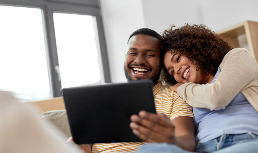 Couple heureux regardant un écran de tablette numérique.