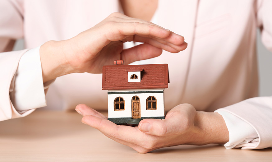 Maquette de maison protégée par les mains d’une femme