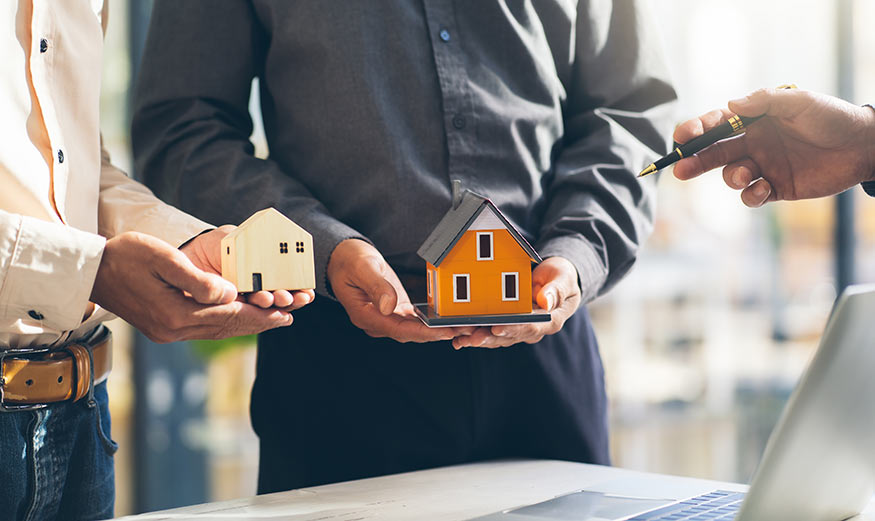 2 personnes tenant 2 maisons miniatures.