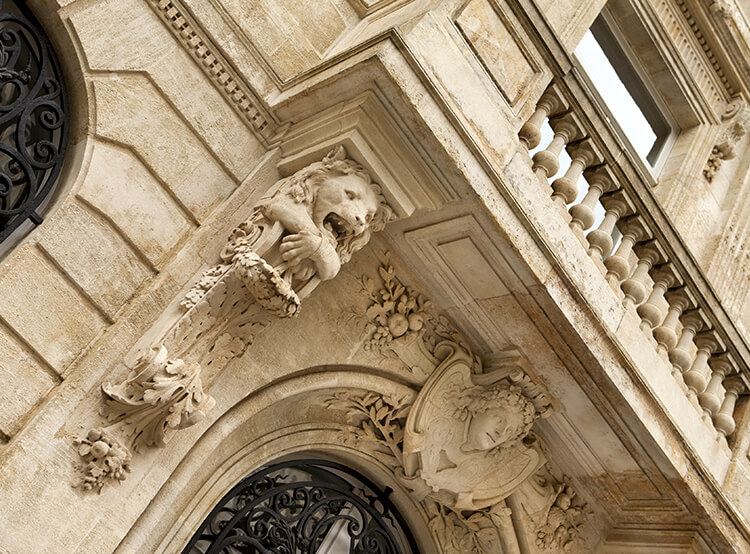 Moulures et lion sculpté en dessous d’un balcon d’un immeuble ancien de prestige