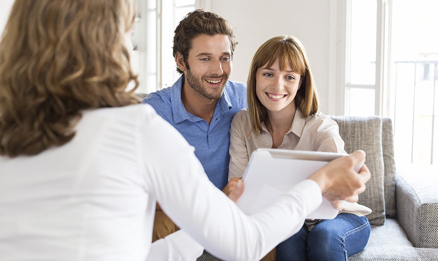 un conseiller immobilier montrant une tablette à un couple.