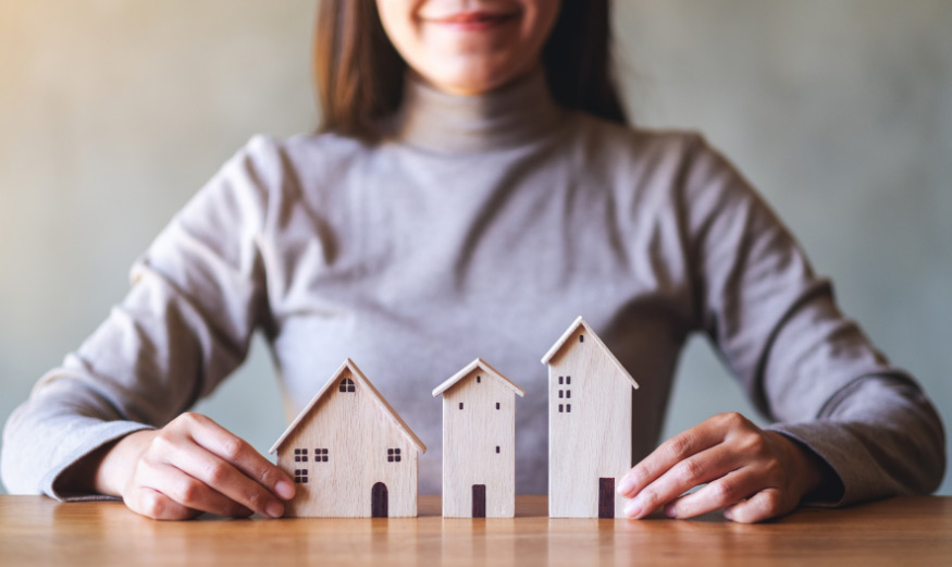 Gros plan d'une femme tenant des modèles de maisons en bois sur la table.