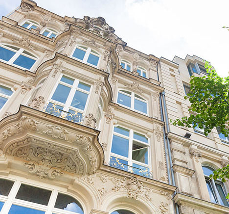 Vue du bas sur la façade d’un immeuble ancien prestigieux aux grandes fenêtres et moulures