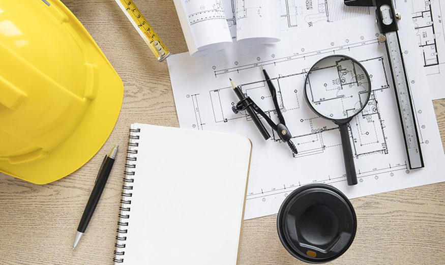 Photo d'un casque de chantier, une loupe et un plan de construction.