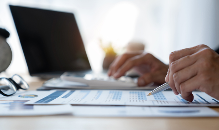 Personne tenant un stylo et parcourant une feuille d’impôts.