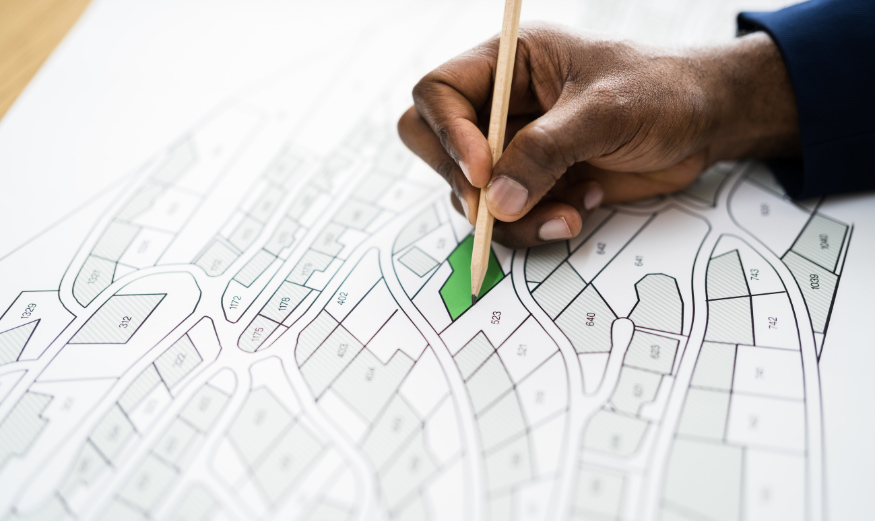 Main tenant un crayon au-dessus d’un plan de terrains à bâtir
